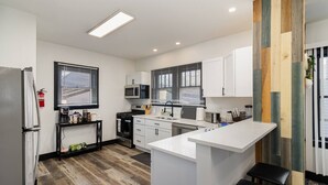 A modern kitchen with white cabinets, a central island, and a black countertop. - Sand & Sun Getaway | Drive to Beach Game Room + 2 Living Areas |Game Room | Minutes to Beach (Michigan City)