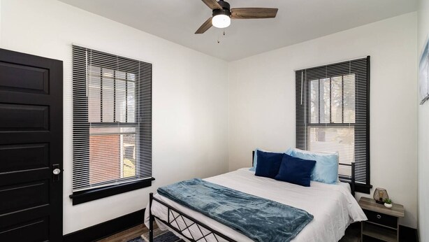 A bedroom with a bed, a ceiling fan, and two windows with blinds. - Sand & Sun Getaway | Drive to Beach Game Room + 2 Living Areas |Game Room | Minutes to Beach (Michigan City)