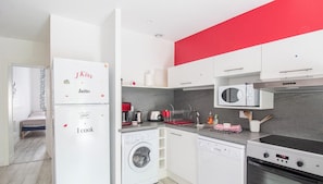 Una cocina moderna con lavadora, lavavajillas, microondas y una pared de acento roja.