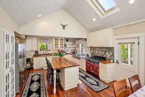 A spacious kitchen with a central island, white cabinetry, and a skylight.