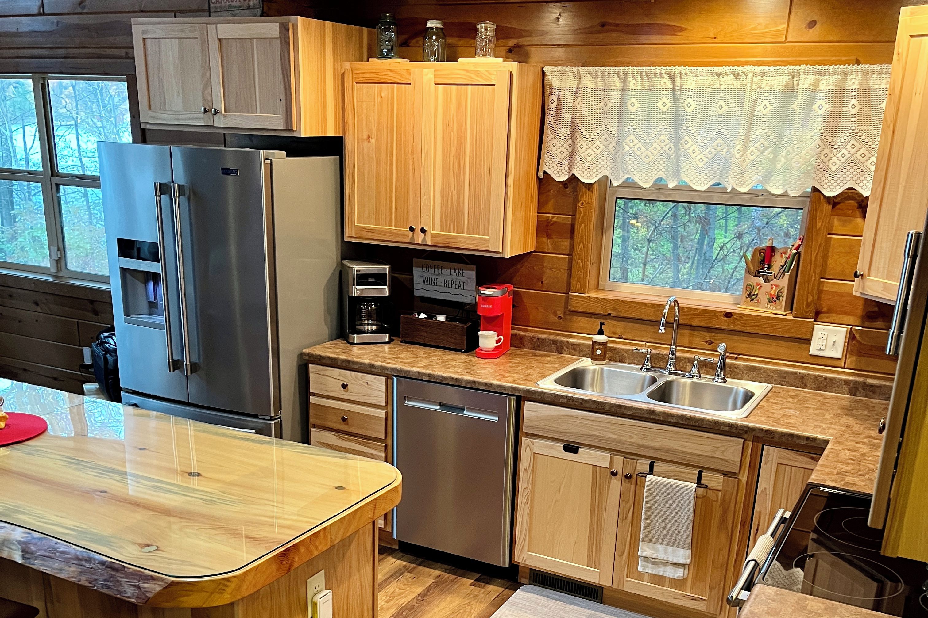 A kitchen with wooden cabinets, a stainless steel refrigerator, a coffee maker, and a sink.