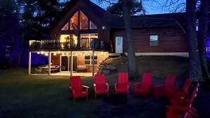 Een houten chalet met twee verdiepingen, een balkon en een overdekt terras.