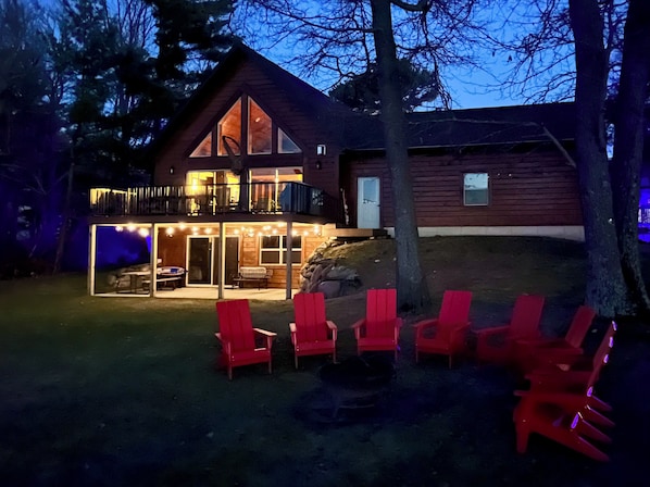 A two-story wooden cabin with a balcony and a covered patio area.