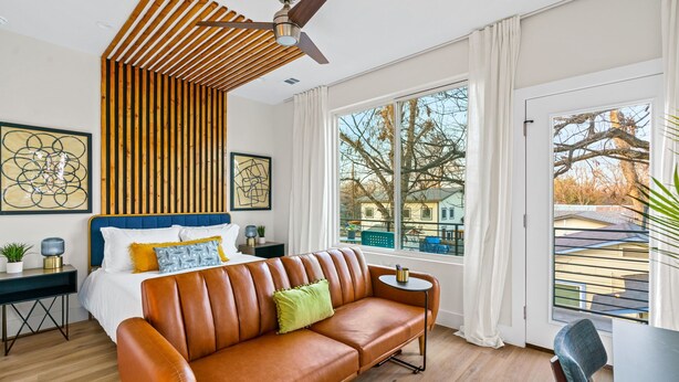 Quarto moderno com uma cama grande, um sofá de couro e um ventilador de teto.
