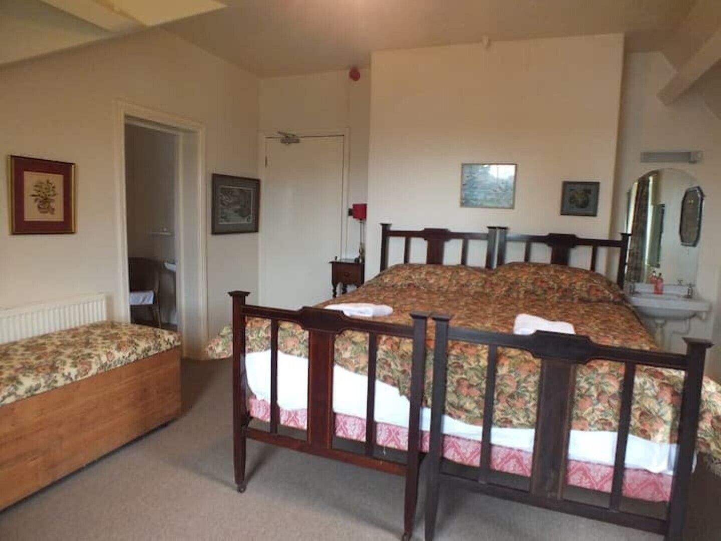 Ein Schlafzimmer mit einem hölzernen Bett, einem Nachttisch, einem Sessel, einer Heizung und einer Tür zu einem anderen Raum.