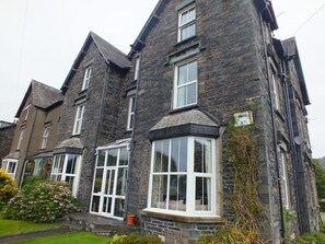 A stone building with multiple windows and a well-maintained garden. - Big house for big holidays (Coniston)
