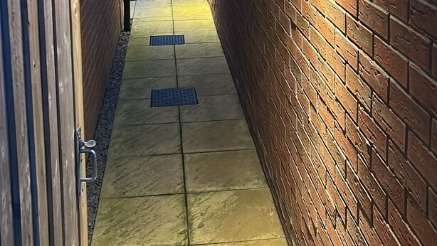 A narrow brick corridor with a tiled floor and a wooden gate on the left. - Comfortable 5-Guest Abode -  in Quiet Village (Grantham)