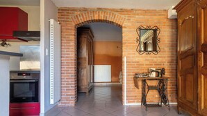 A kitchen with a brick archway, a wooden cabinet, a radiator, and a sewing machine.