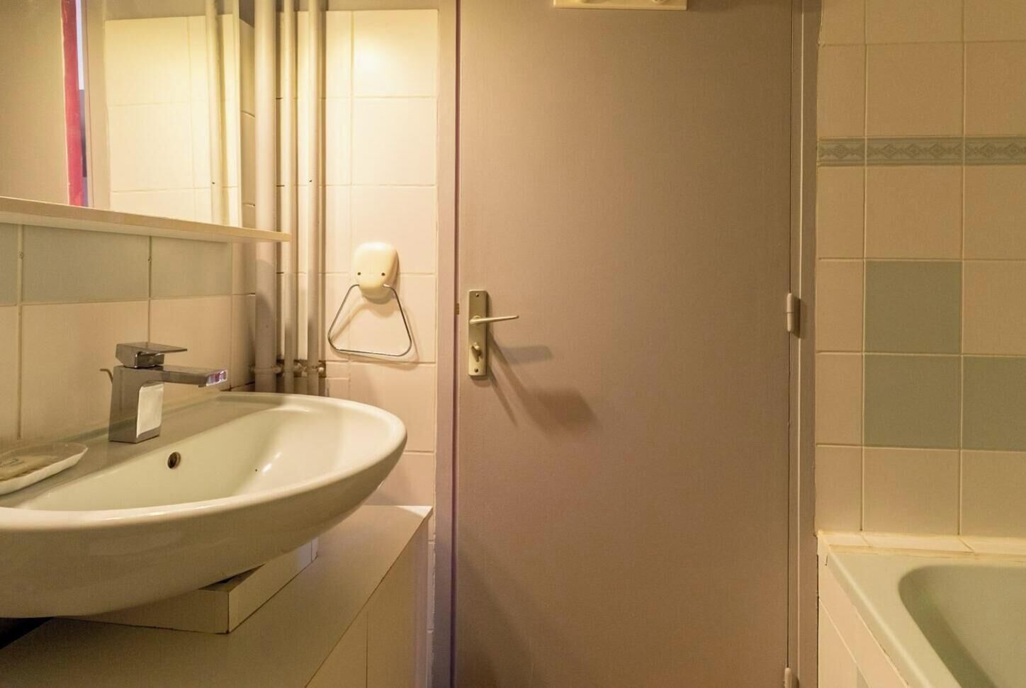 A bathroom with a sink, mirror, towel rack, and a door leading to a shower area.