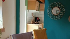 A room with two rocking chairs, a kitchen area, and a teal accent wall.