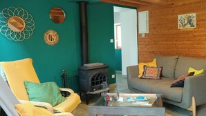 A cozy living room with a sofa, armchair, and a wood-burning stove.