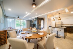 Un comedor moderno con una mesa redonda, sillas y una cocina al fondo.