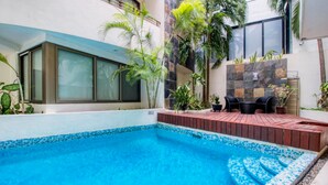 A swimming pool with a tiled edge, surrounded by a wooden deck and potted plants. - Luxury 2 Bedroom Condo at Haab (Playa del Carmen)