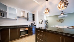 A modern kitchen with dark cabinetry, a large island, and pendant lighting. - Luxury 2 Bedroom Condo at Haab (Playa del Carmen)