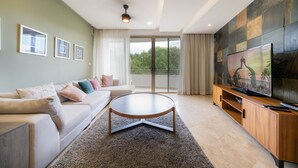 A modern living room with a sofa, coffee table, and TV. - Luxury 2 Bedroom Condo at Haab (Playa del Carmen)