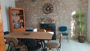 Uma sala de jantar com parede de pedra, mesa de madeira e cadeiras.