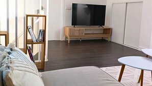 Un dormitorio estilo loft moderno con una cama grande, un televisor y una estantería.