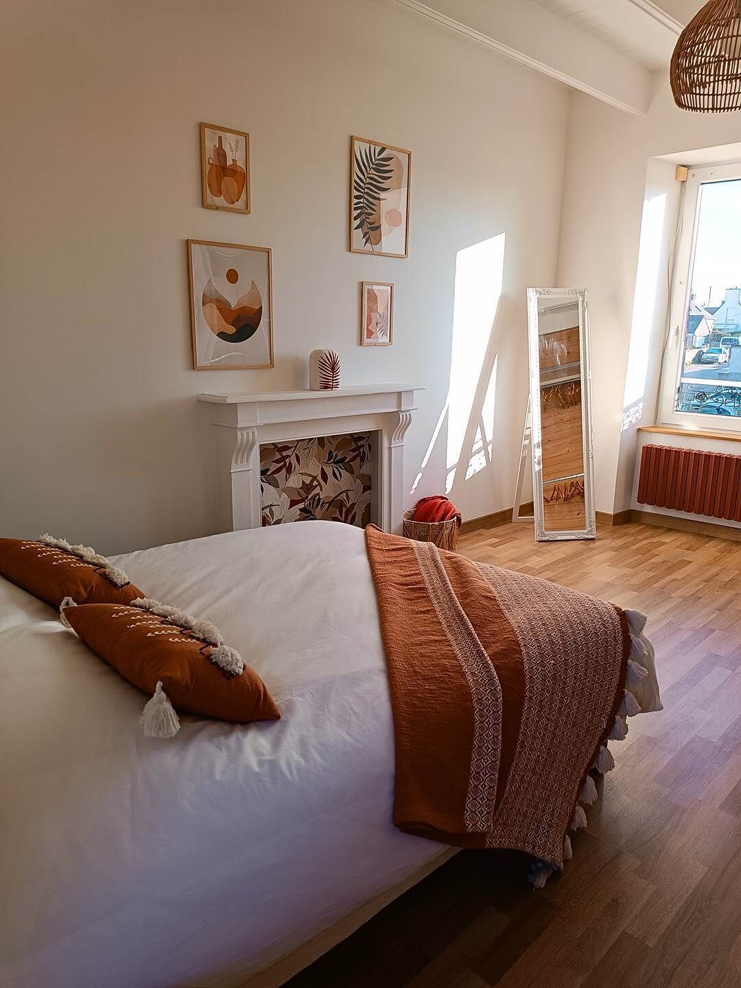 Une chambre à coucher avec un lit, une cheminée et des œuvres d’art accrochées au mur.
