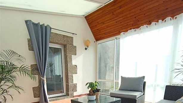Uma área de estar externa moderna com um sofá, uma mesa de centro e um vaso de planta.