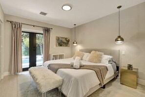 A bedroom with a large bed, a bench, a bedside table, and a view through a glass door. - Saltwater Pool, Firepit & Workspace I 7 min to Brickell (Miami)