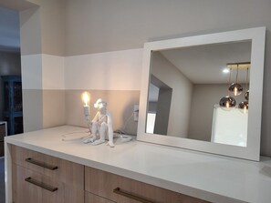 A bathroom vanity with a mirror, a light fixture, and a white decorative object. - Saltwater Pool, Firepit & Workspace I 7 min to Brickell (Miami)