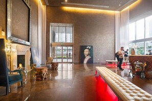 Un hall espacioso con chimenea, un retrato grande y un banco.