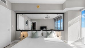 A modern bedroom with a large bed, a mirrored wall, and a TV. - Sunrise Water Views I Pool, Spa, Gym & Free Parking (Miami)