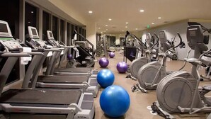 Uma academia com esteiras, elípticos e bolas de exercício.
