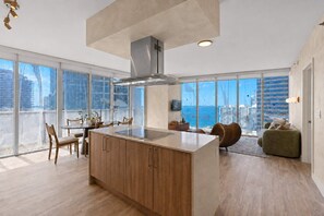 A modern kitchen with a central island, large windows, and a view of the city. - Water View Retreat I Pool, Spa, Gym & Free Parking (Miami)