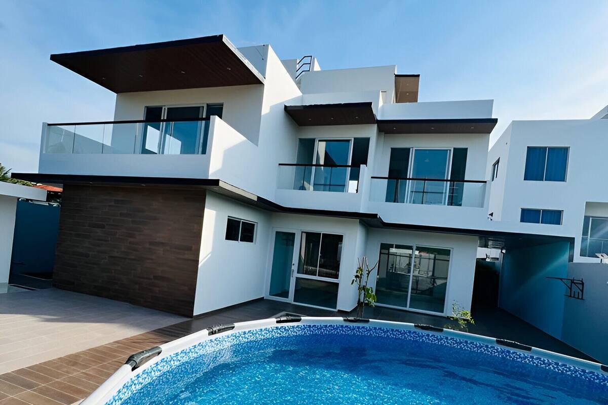 A modern two-story house with a swimming pool in the foreground.