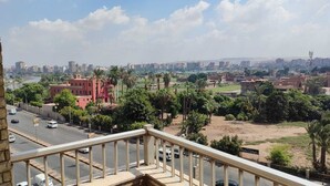 Un paisaje urbano con un edificio rojo destacado, una carretera con vehículos y un cielo despejado.