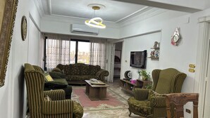 Una sala de estar con un sofá, dos sillones, una mesa de centro y un televisor.