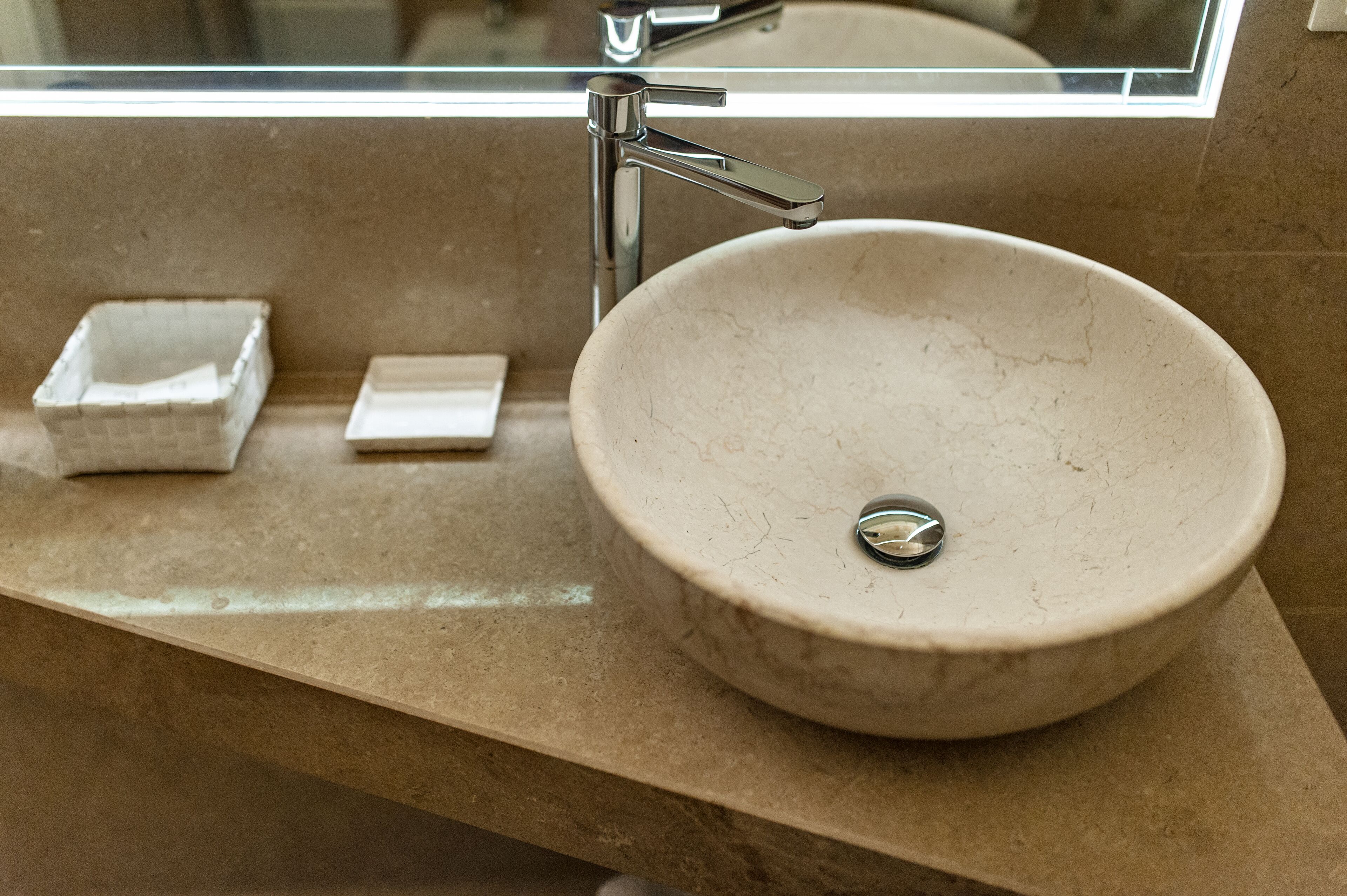 A bathroom with a round marble sink, a chrome faucet, and a small square soap dish.