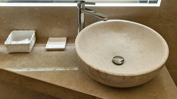 A bathroom with a round marble sink, a chrome faucet, and a small square soap dish.
