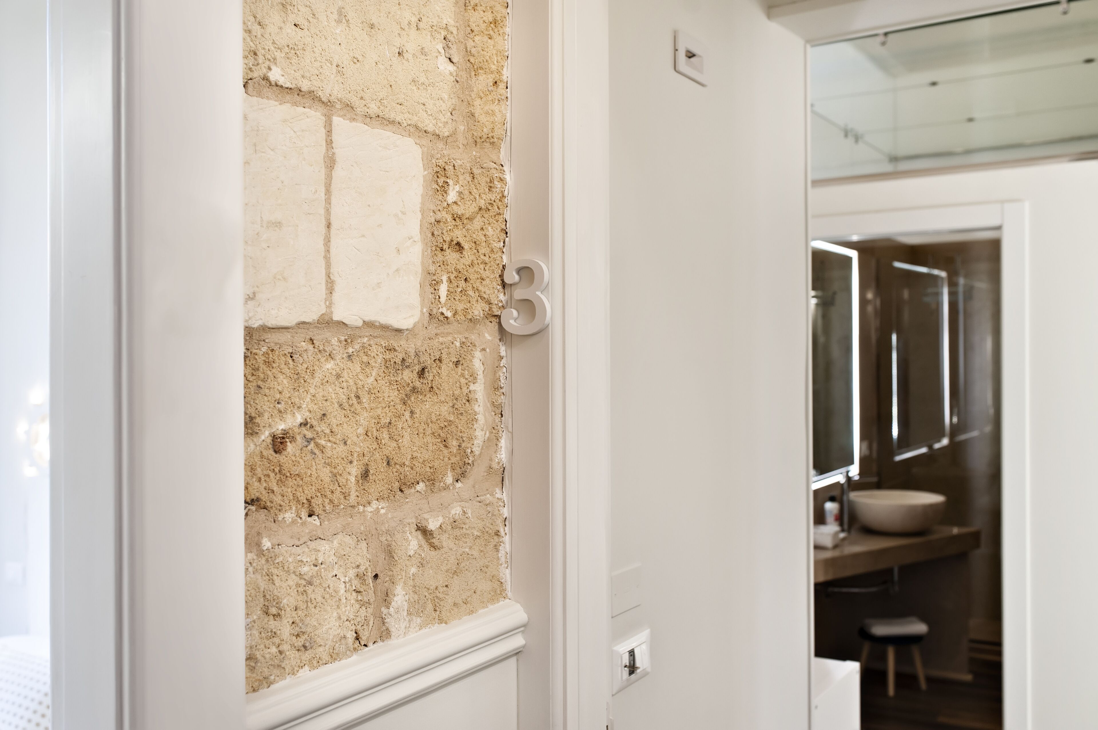A bathroom with a white sink, a mirror, and a stool.