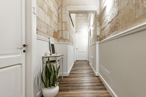 Un pasillo con paredes blancas, suelo de madera y una planta en maceta.