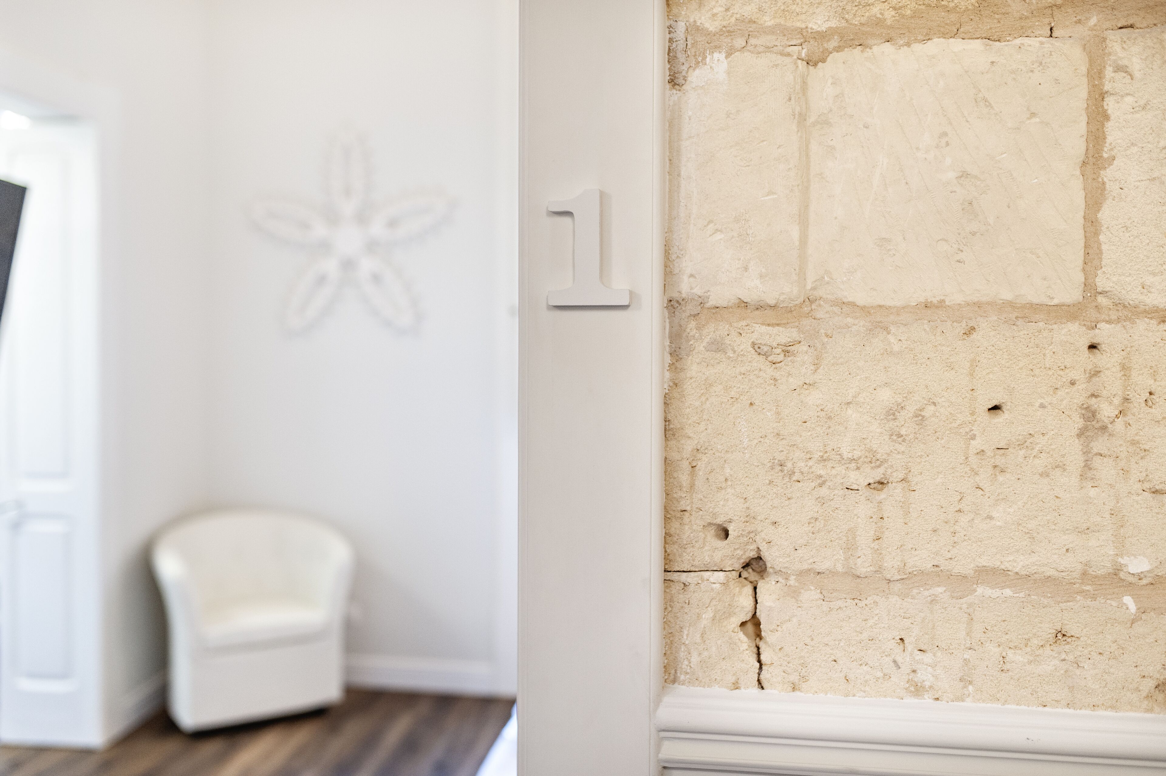 Una habitación con una pared blanca, una silla blanca y una pared de ladrillo con un cartel con el número 1.