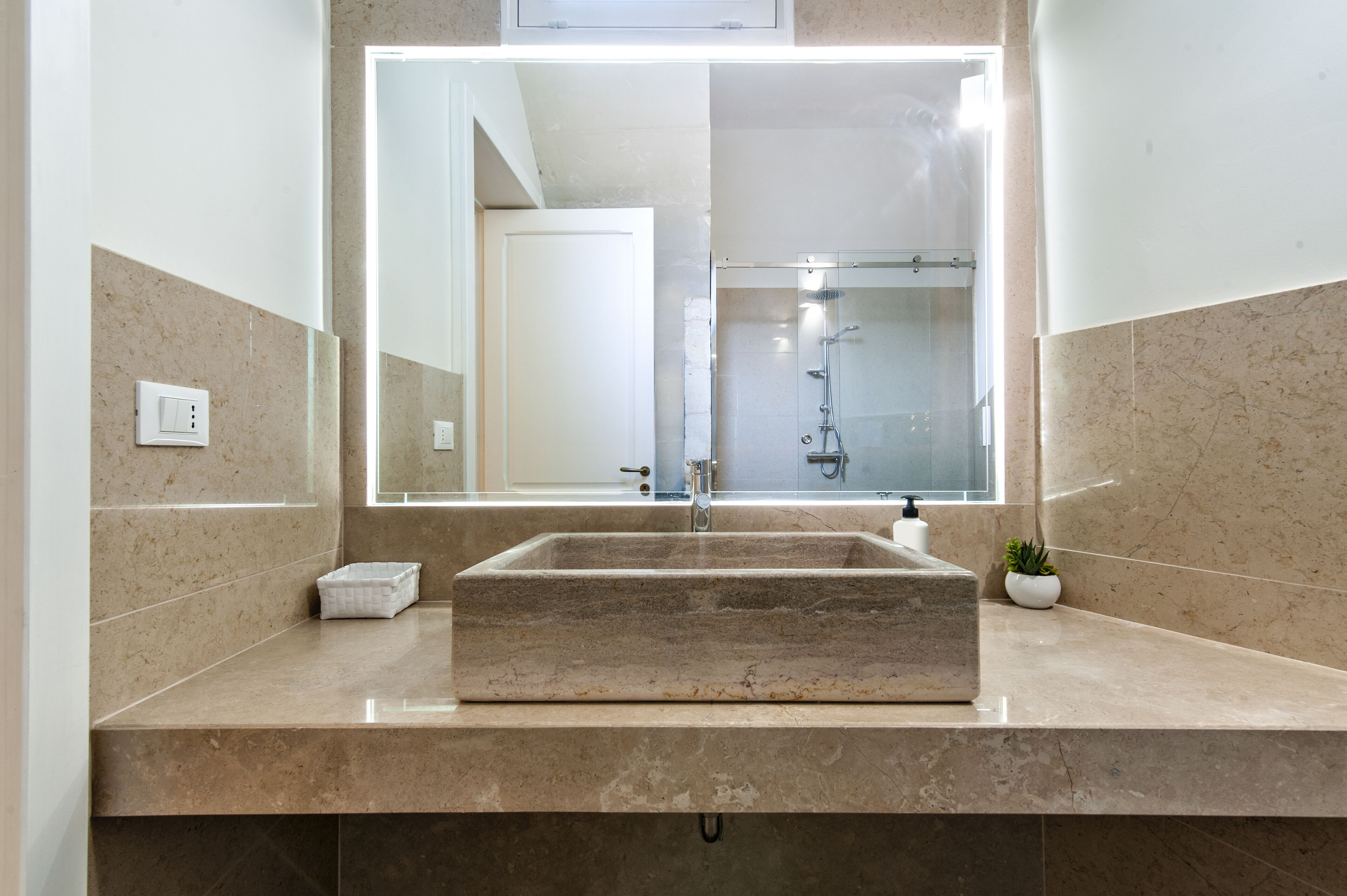 A bathroom with a large mirror, a rectangular sink, and a shower.