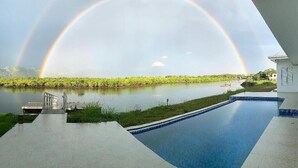 A swimming pool with a view of a river and a rainbow. - Lake Side Deluxe Villa (Nadi)