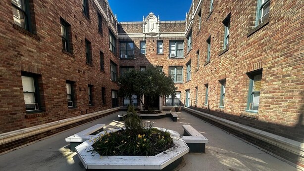 A courtyard with brick buildings, a central planter with flowers, and a clear blue sky. - Vintage Studio in Belltown-Space Needle (Seattle)
