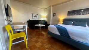 A hotel room with a bed, a desk, a chair, a sofa, and a lamp. - Vintage Studio in Belltown-Space Needle (Seattle)
