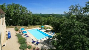 A swimming pool with lounge chairs and umbrellas, surrounded by trees and hills. - Beautifully Finished House, Modern Interiors, Private Heated Pool & Fabulous Location near Martel! (Martel)