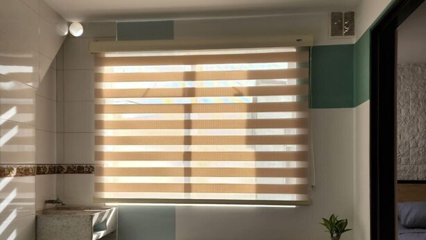 Um banheiro moderno com uma janela grande, um banco e uma planta em vaso.