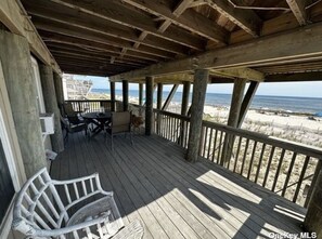 Enjoy the ocean view from this deck with a wicker chair and access to the beach.