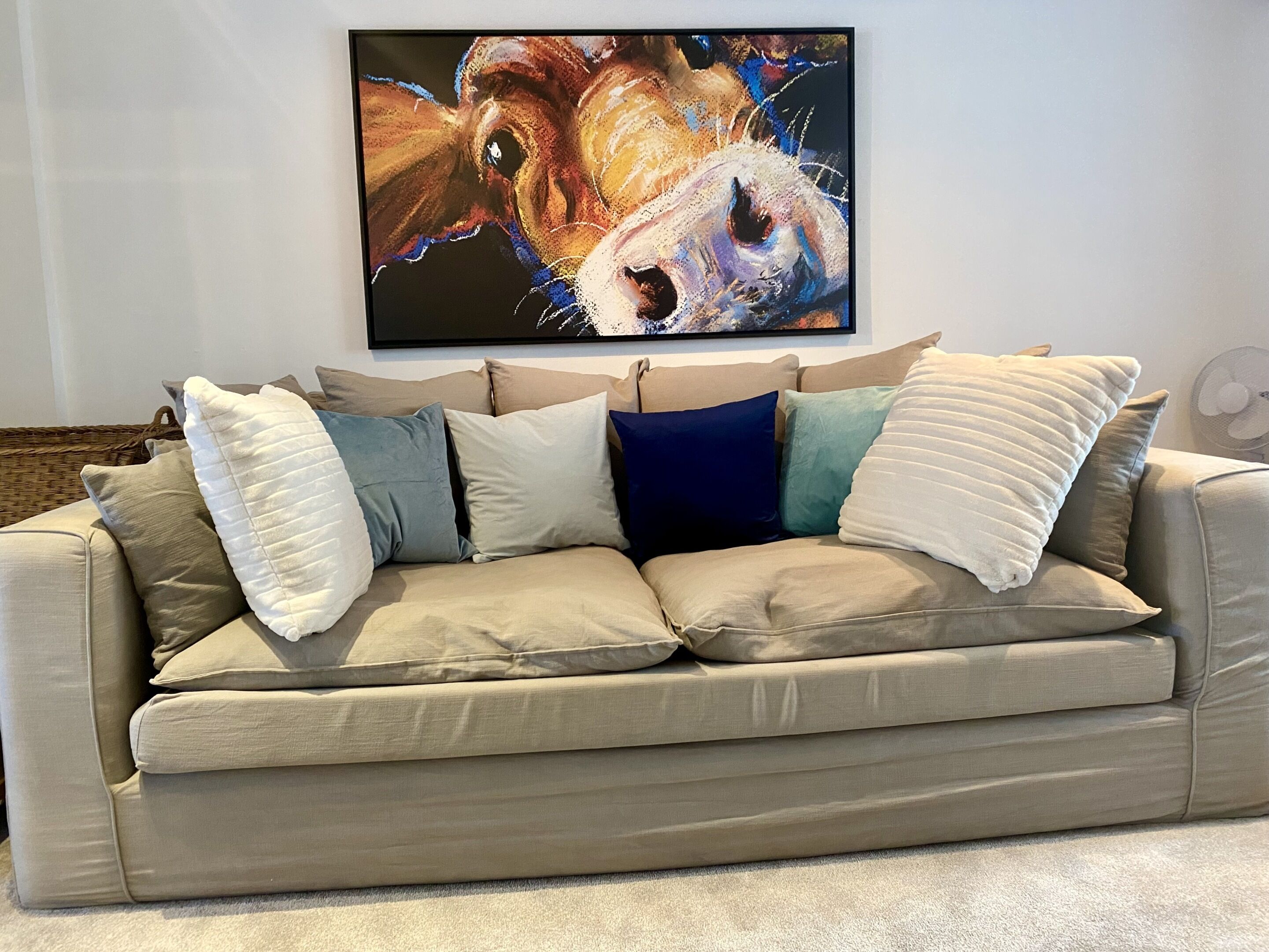 A beige sofa with multiple cushions in a living room.