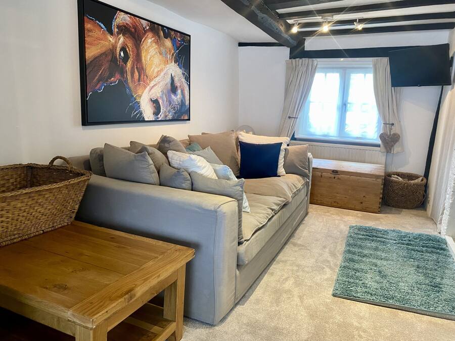 A cozy living room with a sofa, a wooden table, a large painting, and a window with curtains.