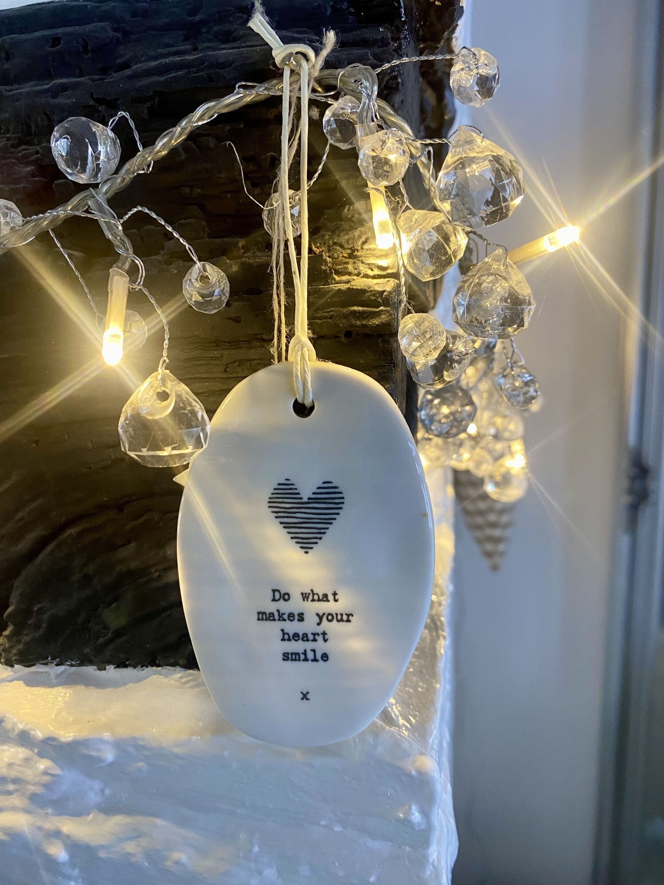 A decorative ornament with a heart and a motivational message, hanging above a textured surface.
