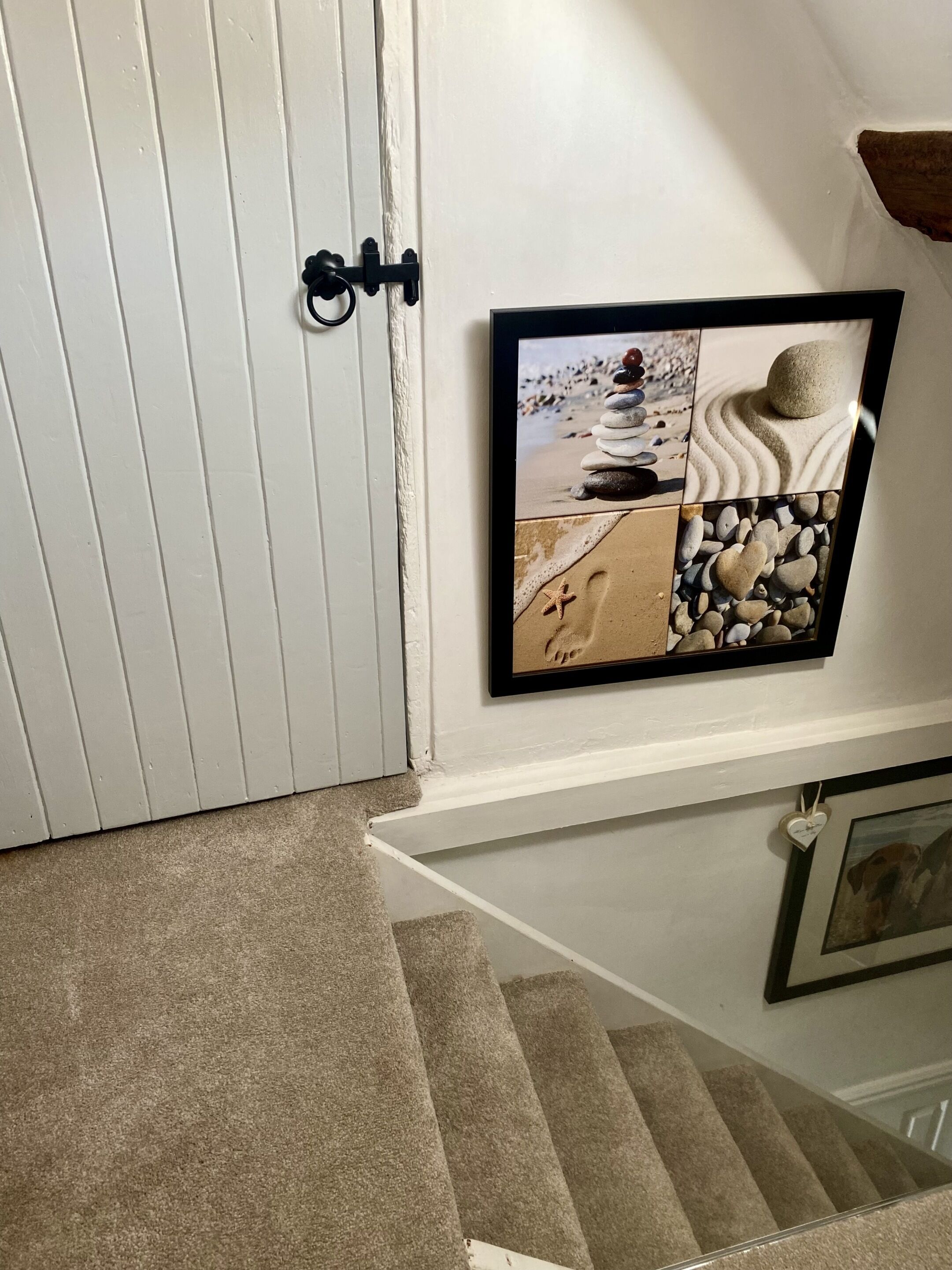 A staircase with a carpeted landing and a framed artwork depicting beach scenes.