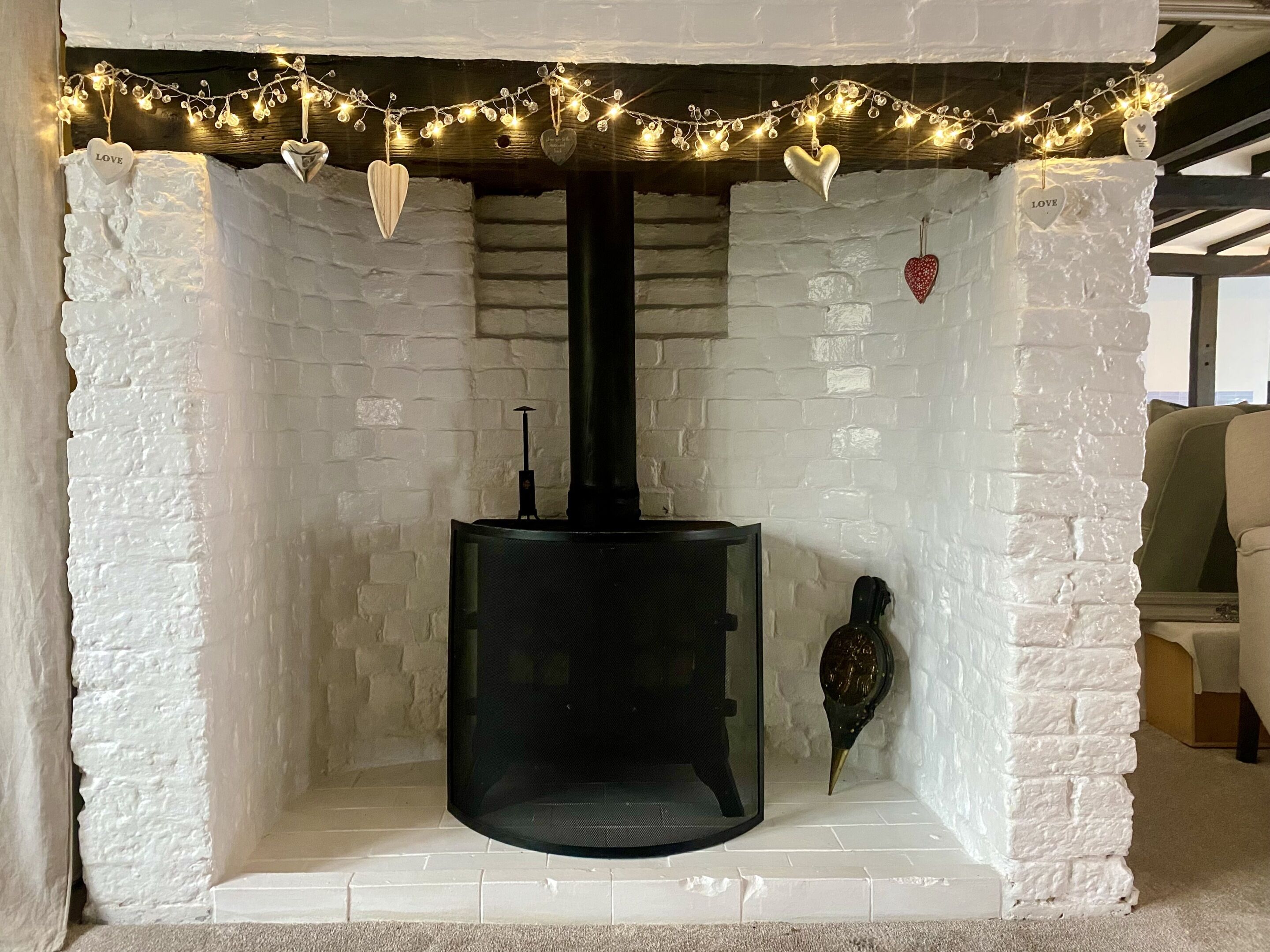 A fireplace with a black chimney, surrounded by white brick walls and a white mantelpiece.