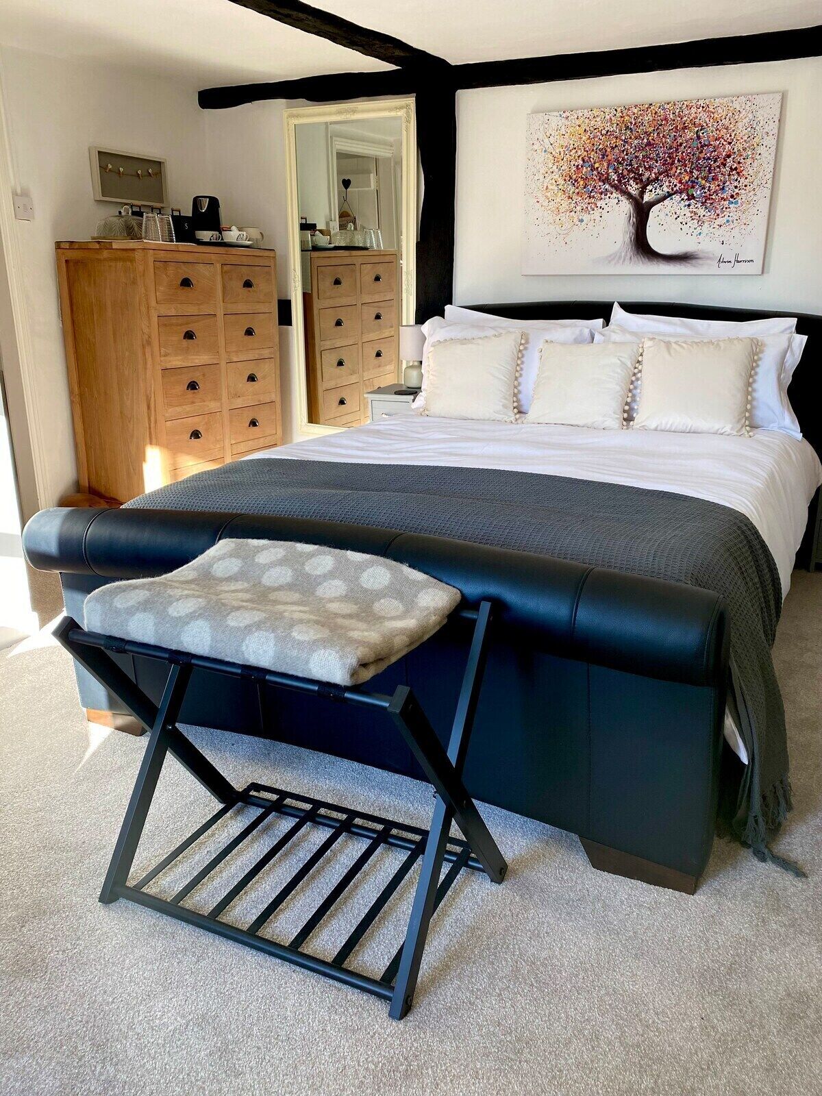 A bedroom with a bed, a wooden dresser, a chair, and a painting on the wall.